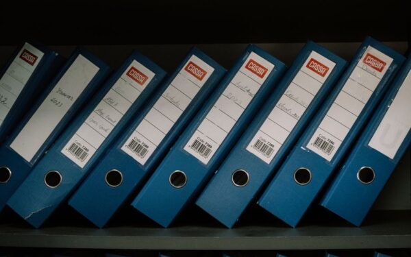Neatly arranged blue office binders labeled with dates and names for organized storage.