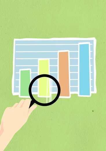 Top view of decorative cardboard illustration of hand with magnifying glass above diagram with columns on green background